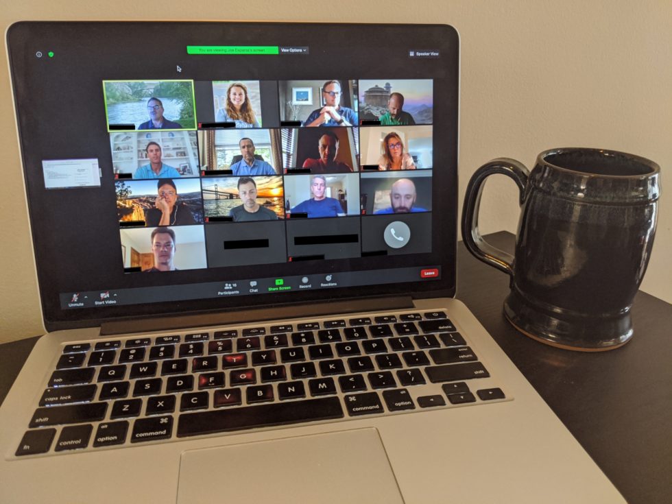 Laptop computer showing a virtual meeting with pictures of the attendees